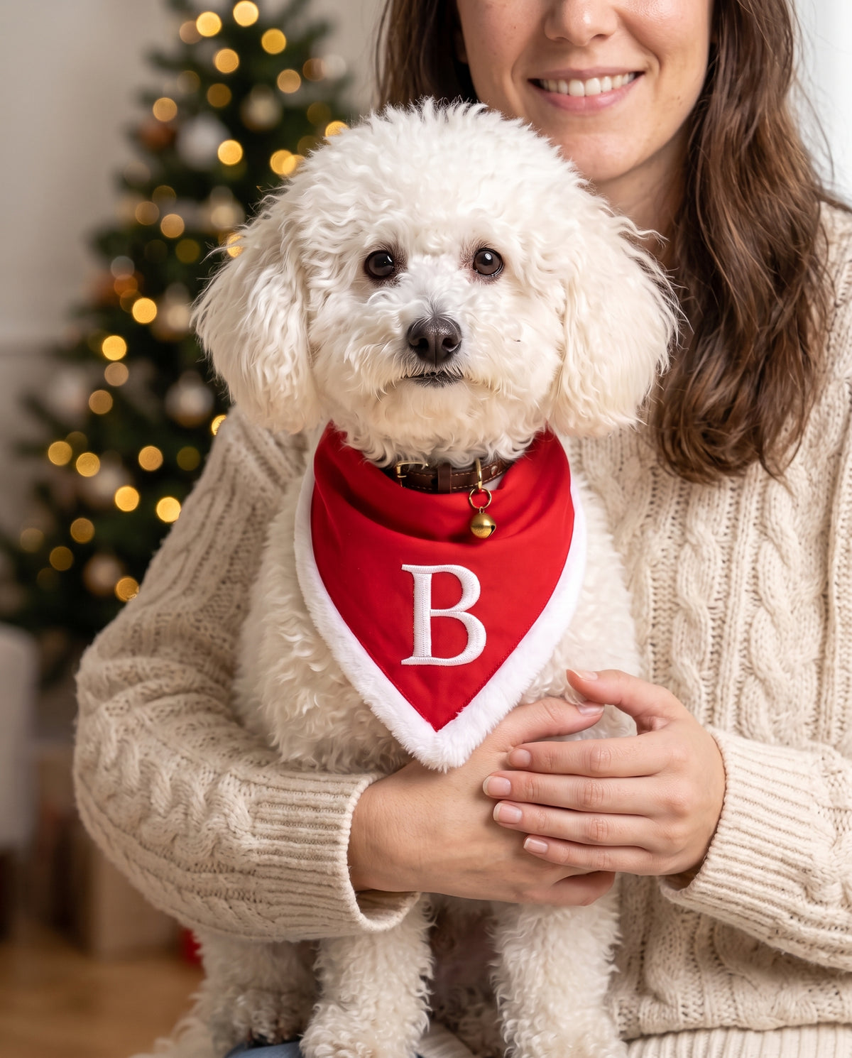 Ben in braccio con la bandana di Natale rossa e l'iniziale B ricamata, davanti all'albero
