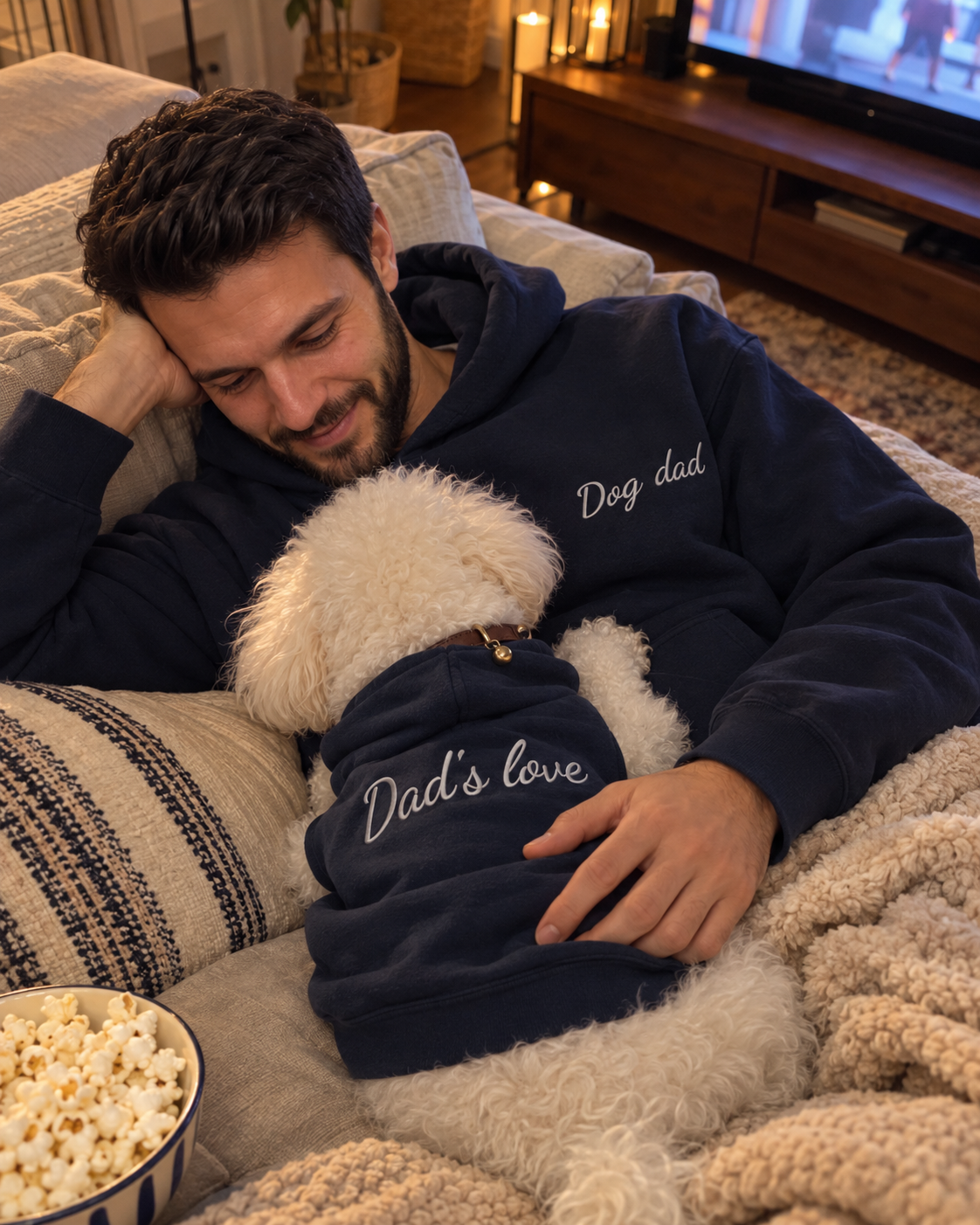 Set felpe abbinate Dog dad + Dad's love blu navy: uomo con felpa Dog dad ricamata sul divano con il cane in felpa Dad's love