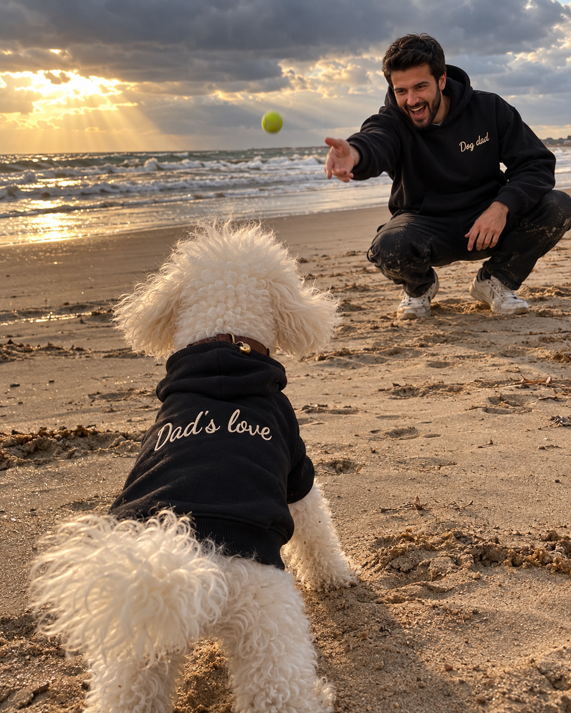 Set felpe abbinate Dog dad + Dad's love nero: uomo con felpa Dog dad ricamata in spiaggia che gioca con il cane in felpa Dad's love