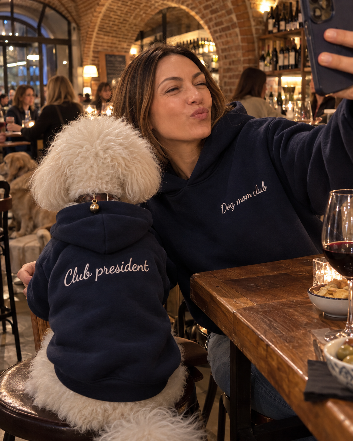 Set felpe abbinate Dog mom club + Club president blu navy: donna con felpa Dog mom club ricamata e cane con felpa Club president al ristorante