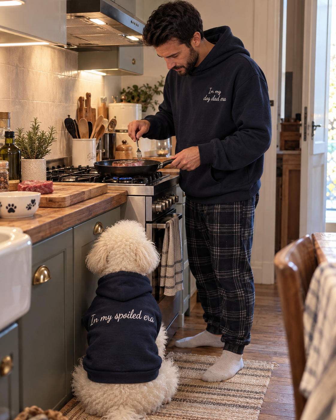 Set felpe abbinate In my dog dad era + In my spoiled era blu navy: uomo in cucina con felpa ricamata e cane con felpa In my spoiled era