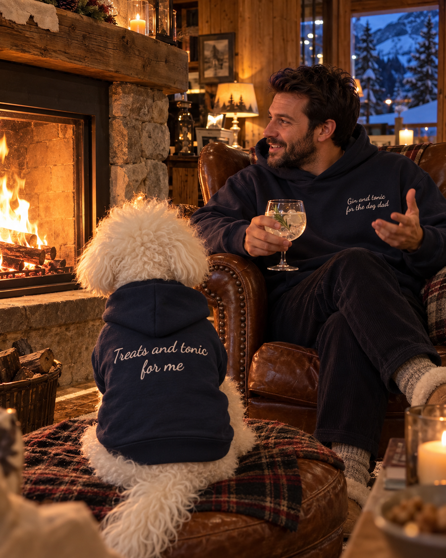Set felpe abbinate Gin and tonic for the dog dad + Treats and tonic for me blu navy: uomo davanti al camino con gin tonic e cane con felpa ricamata